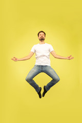 Fototapeta na wymiar Full length portrait of happy jumping man isolated on yellow background. Caucasian male model in casual clothes. Freedom of choices, inspiration, human emotions concept. Getting calm.