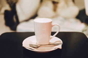 Hot milk in white ceramic cup with Teaspoon on the wooden table.