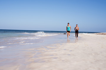 Couple running on a sandy white beach