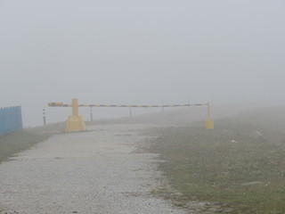 Barrier, located on the road autumn foggy morning.