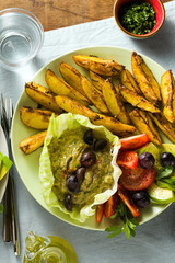 whole plant vegan lunch or dinner of baked potatoes, baba ganoush, tomato and avocado salad. modern healthy food. shot from above.