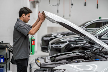 Asian mechanic Checking and Opening the car hood in maintainance service center which is a part of showroom, technician or engineer professional work for customer, car repair concept - obrazy, fototapety, plakaty