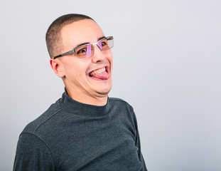 Obraz premium Crazy grimacing man in eye glasses showing the tongue on blue background
