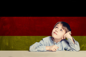 Thinking child boy student against the Germany flag background.