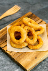 Fried onion rings on wooden cutting board