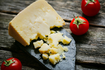 Parmesan reggiano with gastronomic plate and tomato on wooden table