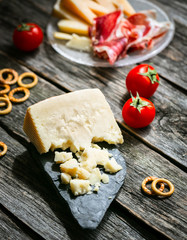 Parmesan reggiano with gastronomic plate and tomato on wooden table