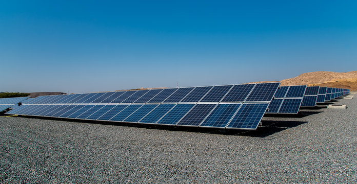 .large solar park, rows of photovoltaic panels, mountains background