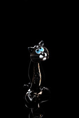 A fugurine of transparent black cat isolated on black background.