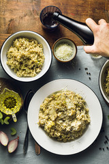 Classic Italian risotto with mushrooms on a wooden table with a blue linen tablecloth. red wine. bottle and glasses. top shots, male hand pours wine