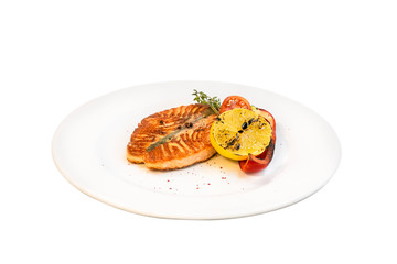 Grilled salmon steak with grilled lemon and vegetables isolated on white background