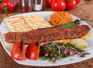Adana barbecue service on a plate with grits, tomatoes and green peppers