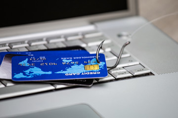 Credit card phishing. Piles of credit cards with a fish hook on computer keyboard. Credit card phishing scam with credit card in fishing hook