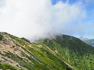 北アルプスの表銀座登山道（燕岳～大天井岳）を歩く登山者　奥に槍ヶ岳が見える