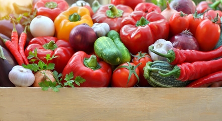 Harvest fresh vegetables in a wooden box with copy space below. Healthy and organic food.