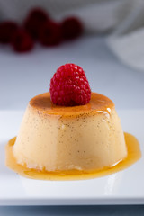 Mini flan with caramel sauce and raspberry garnish
