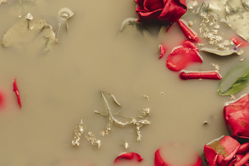 Top view red roses and petals in brown colored water