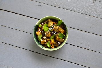Fried eggplant with garlic, cilantro in ginger and soy sauce, top view, copy space