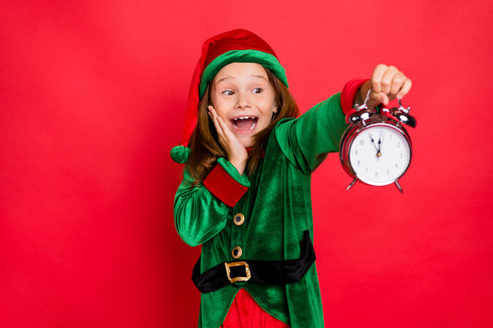 Close-up portrait of her she nice attractive cheerful cheery surprised shocked glad funny pre-teen elf holding in hands clock fairy miracle night isolated over bright vivid shine red background
