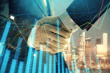 Double exposure of financial chart on cityscape background with two businessmen handshake. Concept of financial analysis and investment opportunities