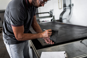 Young engineer setup plasma cutter for work in metalwork workshop.