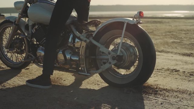 Motorcyclist doing tire burnout in the desert, slow motion. Professional motorcyclist drift and turns on a custom motorcycle on the ground, a biker does a trick on a custom motorcycle
