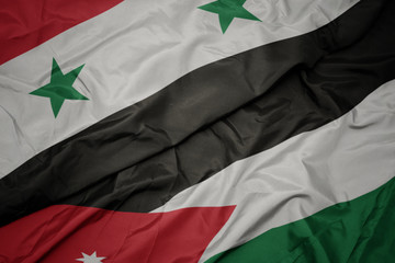 waving colorful flag of jordan and national flag of syria.