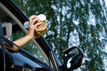 The girl is going to throw a handful of garbage accumulated in the car into the open window of the...