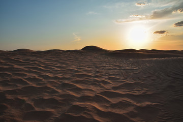 sunset in the Sahara desert over the peaks of sand dunes