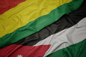 waving colorful flag of jordan and national flag of bolivia.