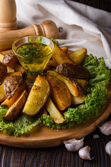 Potato wedges baked in their skins with lettuce on wooden background.