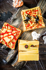Funny Halloween sandwiches for kids breakfast. Child Halloween party food concept. Old rustic wooden background copy space top view