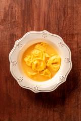 Italian tortellini with broth, shot from above on a dark rustic wooden background with copy space