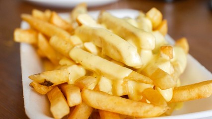 Top French fries with cheese sauce and bacon