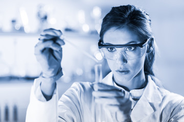 Life scientists researching in laboratory. Focused female life science professional pipetting...