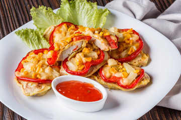 Chicken fillet in a batter with corn, paprika, lettuce and spicy tomato sauce on white plate