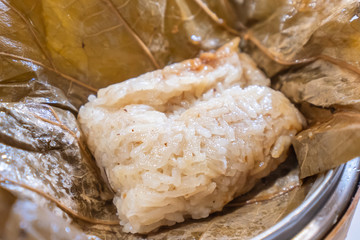 Delicious Lo Mai Gai dim sum, fresh steamed glutinous rice with chicken roll wrapped by lotus leaf in bamboo steamer in hong kong yumcha restaurant.