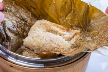 Delicious Lo Mai Gai dim sum, fresh steamed glutinous rice with chicken roll wrapped by lotus leaf in bamboo steamer in hong kong yumcha restaurant.
