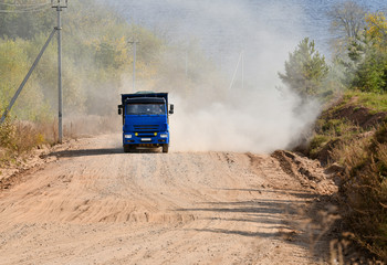 Fototapeta premium A dump truck with a load goes up the mountain along a dirt road.