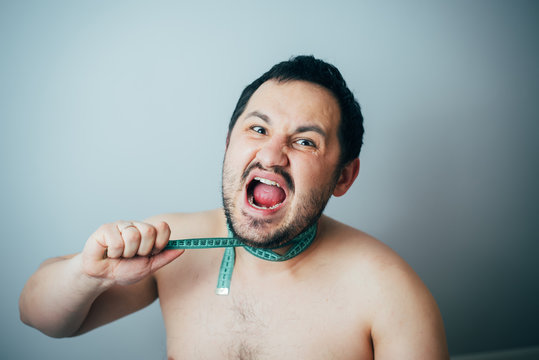 Portrait of overweight man strangles himself with measuring tape concept overweight kills