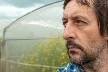 Confident farmer posing in rapeseed  farming field
