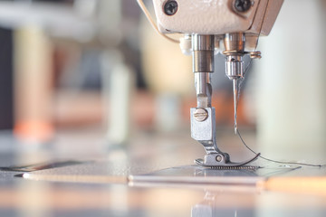 White industrial sewing machine with blurred background close-up.