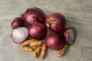 Close-up from above. Red onions and curcuma roots isolated on gray. Selective focus.
