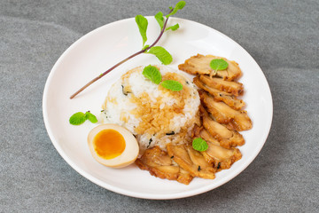 Grill chicken in soy sauce with rice and seaweed in Korean style in white dish on tile table.