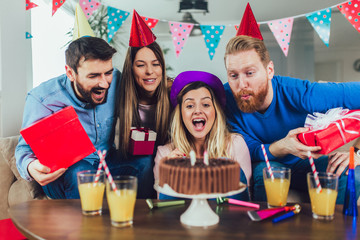 Young group of happy friends celebrating birthday at home and having fun.