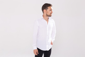 Portrait of handsome happy young man in casual shirt standing against white background with copyspace