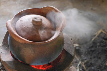Clay pot that is boiling herbal medicine and has smoke on the charcoal stove.