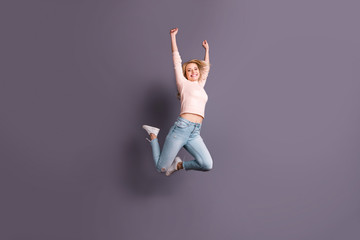 Full length photo of pretty lady jumping high competitive sporty mood raising hands up wear casual stylish outfit isolated grey color background