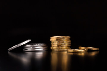 A stack of silver and gold coins. Silver and gold coins on a black background.Coins side view close up.