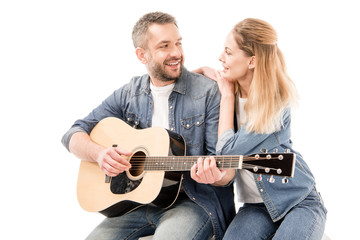 smiling man in jeans playing acoustic guitar for wife isolated on white